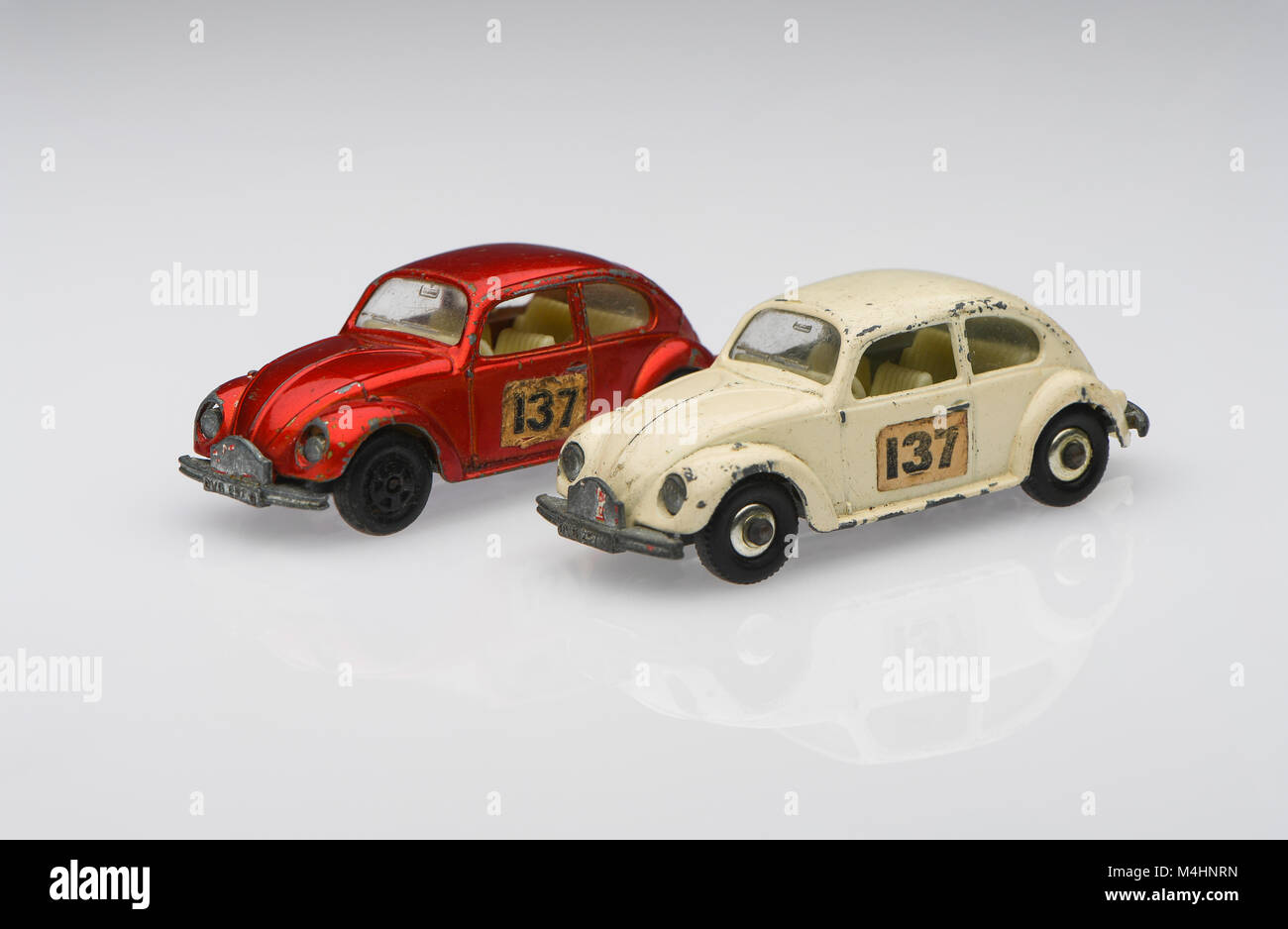 Une paire de blanc et rouge vintage 1500 Volkswagen Coccinelle berline voiture de course voiture jouet montrant des signes d'utilisation sur un fond blanc. Banque D'Images