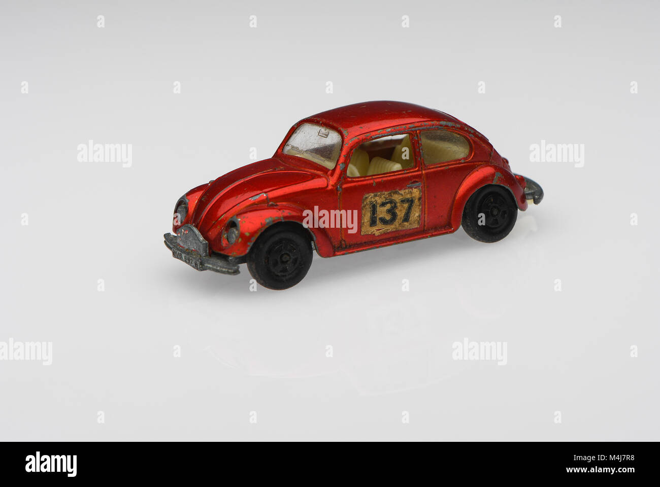 Une berline rouge vintage 1500 Volkswagen voiture de course voiture jouet montrant des signes d'utilisation sur un fond blanc. Banque D'Images