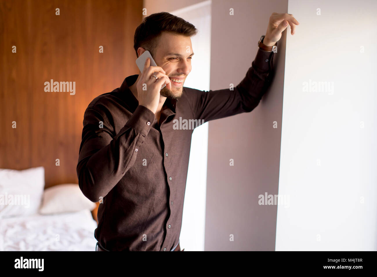 Beau jeune homme à l'aide de téléphone mobile dans la chambre Banque D'Images
