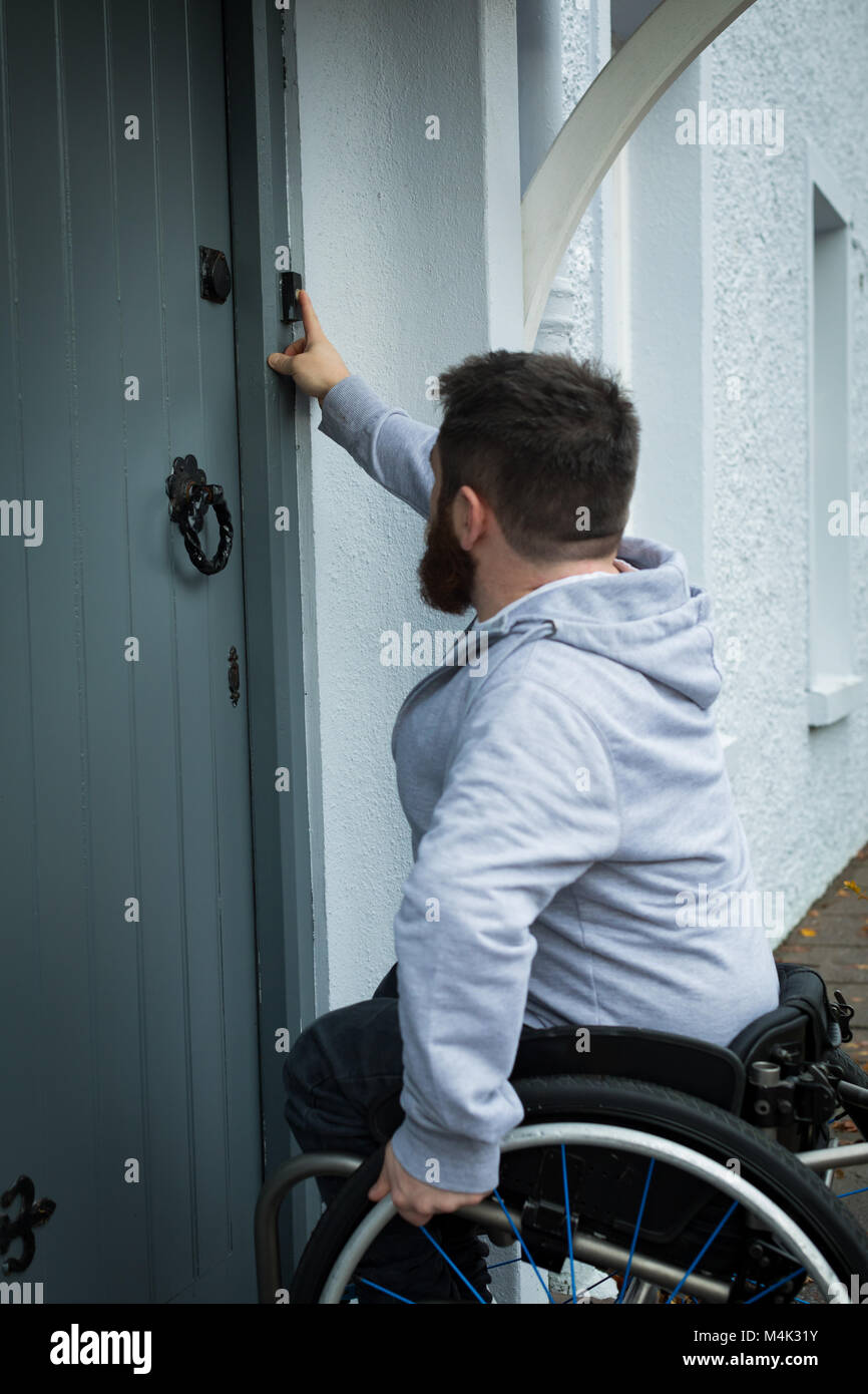 Homme handicapé faire sonner la cloche de porte Banque D'Images