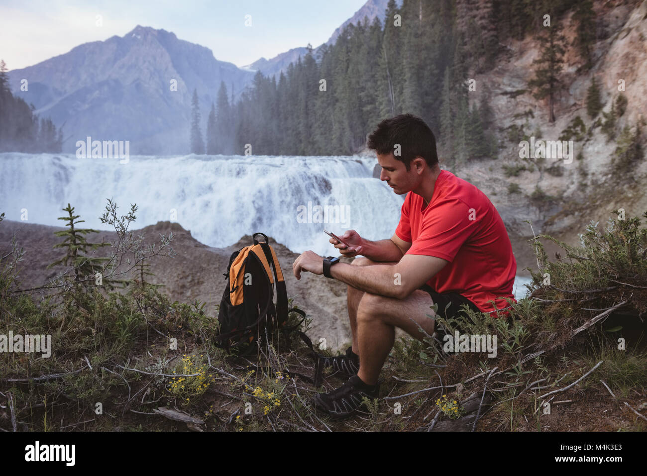 L'homme à l'aide de mobile phone near waterfall Banque D'Images