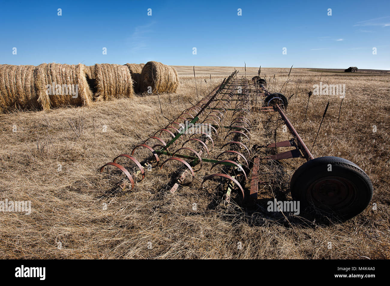 Une pièce d'équipement agricole est assis dans l'herbe par de grandes dales de foin près de Davenport, Washington. Banque D'Images