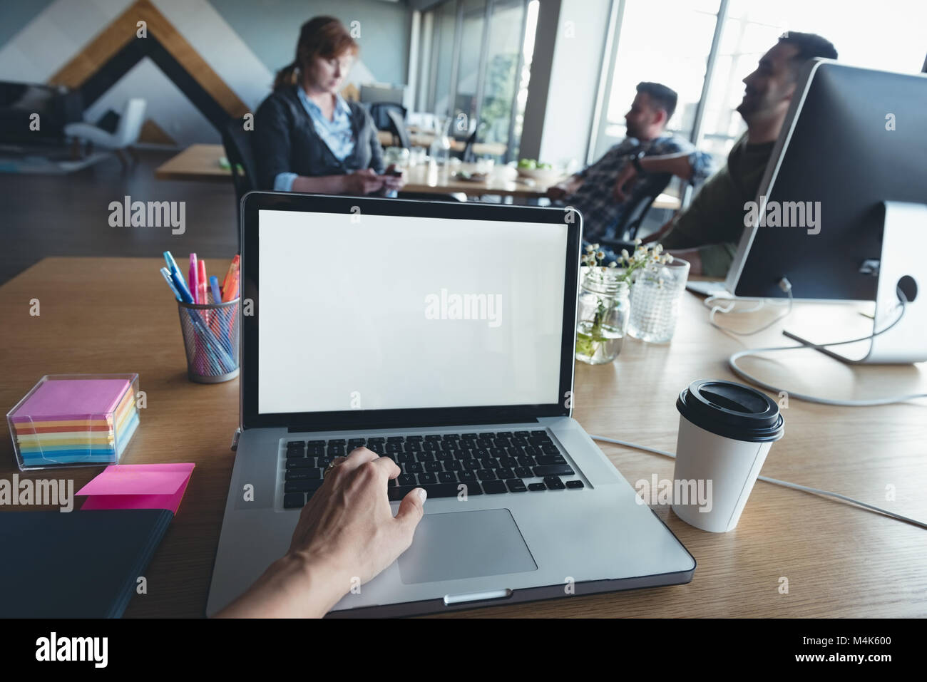 Businessman using laptop alors que collègues having discussion Banque D'Images