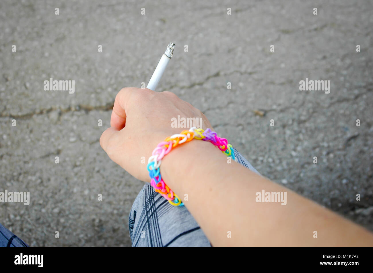 Main de jeune fille à la cigarette et rainbow bracelet gomme close up Banque D'Images