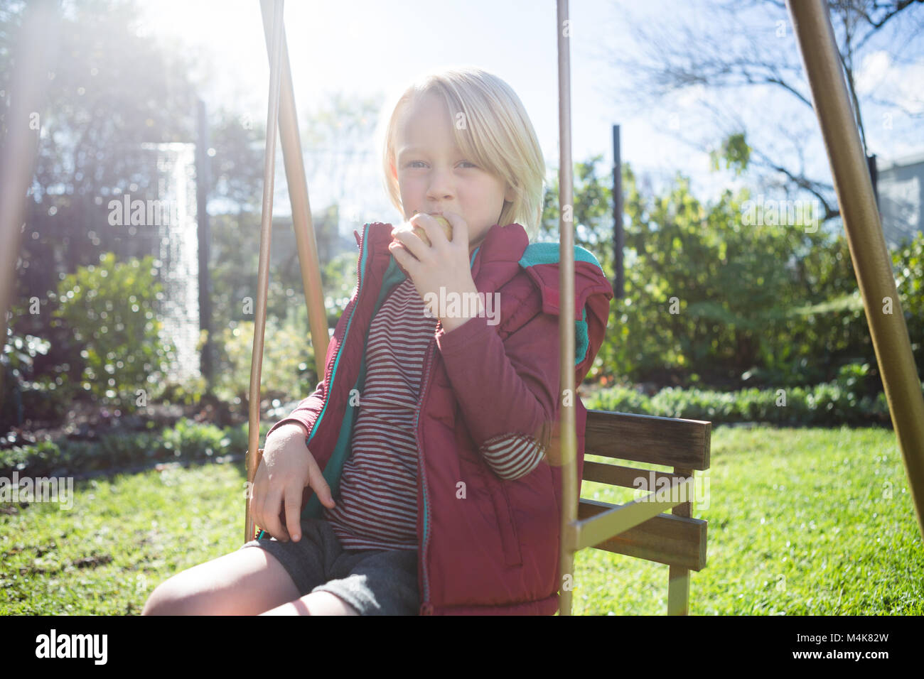 Boy relaxing in swing sur une journée ensoleillée Banque D'Images