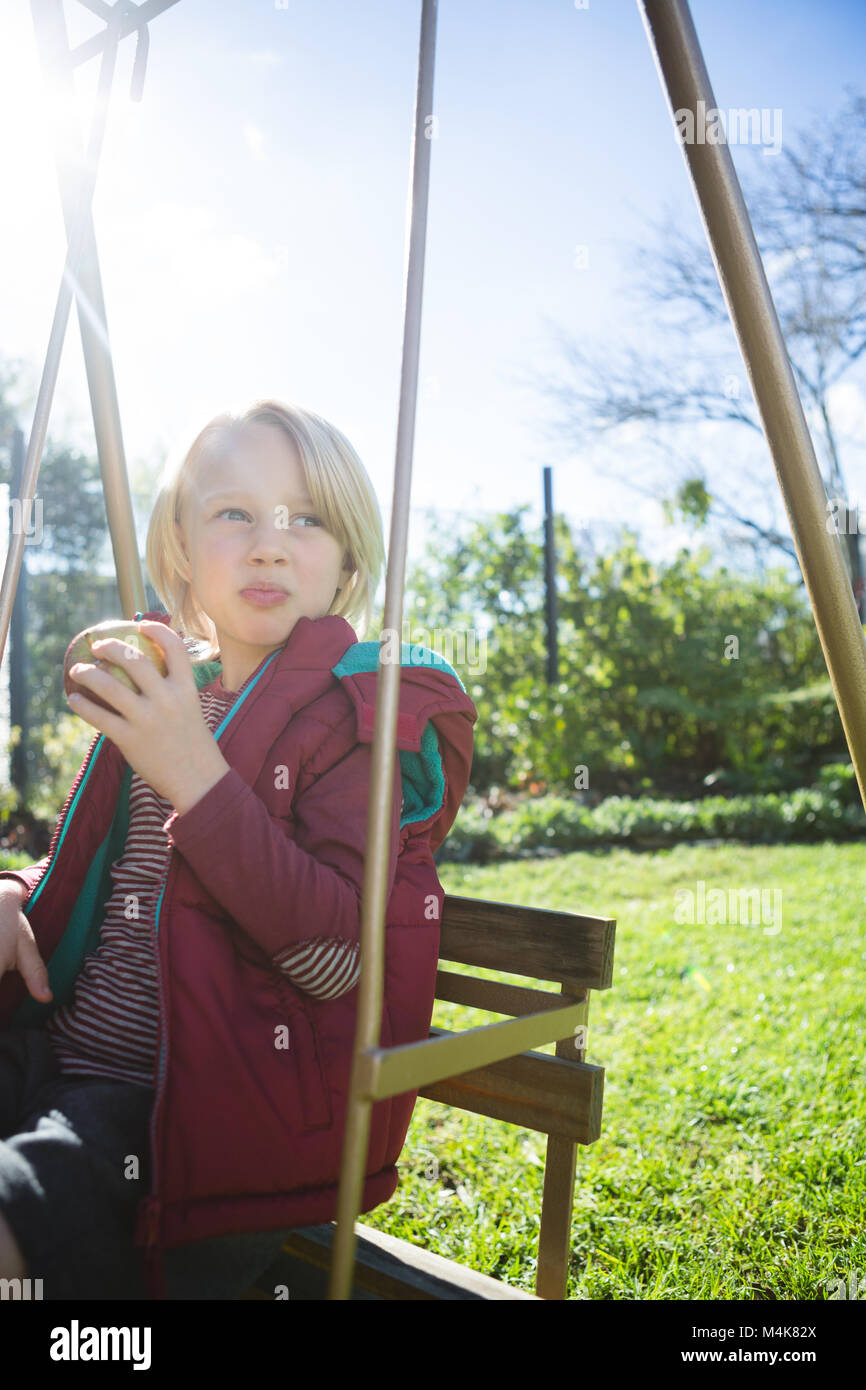 Boy relaxing in swing sur une journée ensoleillée Banque D'Images