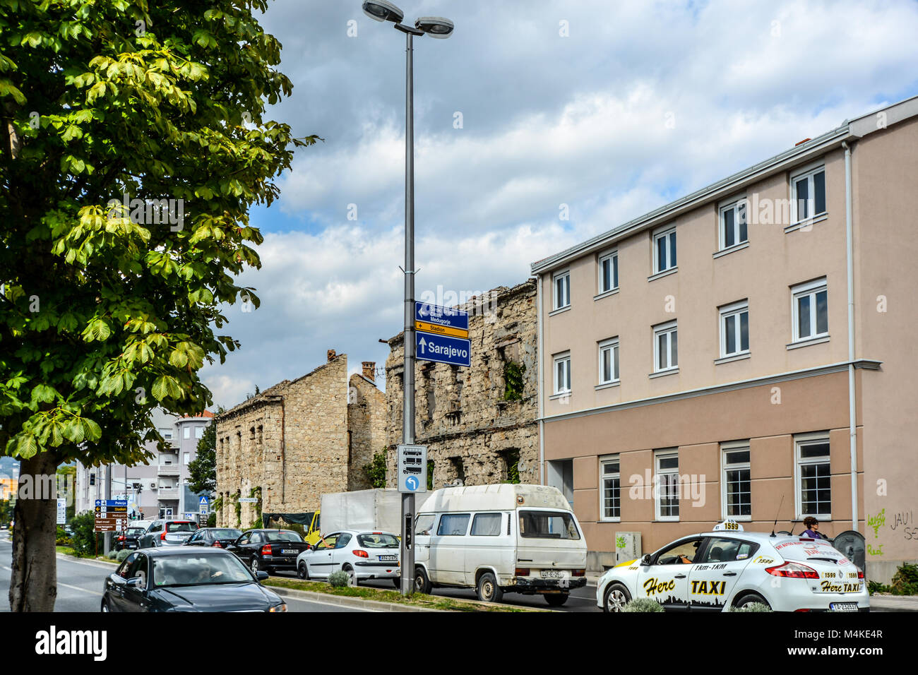 Une rue au centre-ville de Mostar en Bosnie-Herzégovine avec une guerre a ravagé, ruine bombardée d'un bâtiment et un panneau indiquant à Sarajevo Banque D'Images