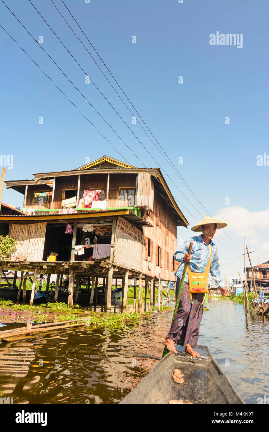 Haspres Thauk : Femme, voile, aviron jambe style, canal, maisons à échasses, ethnie Intha, lac Inle, l'État de Shan, Myanmar (Birmanie) Banque D'Images