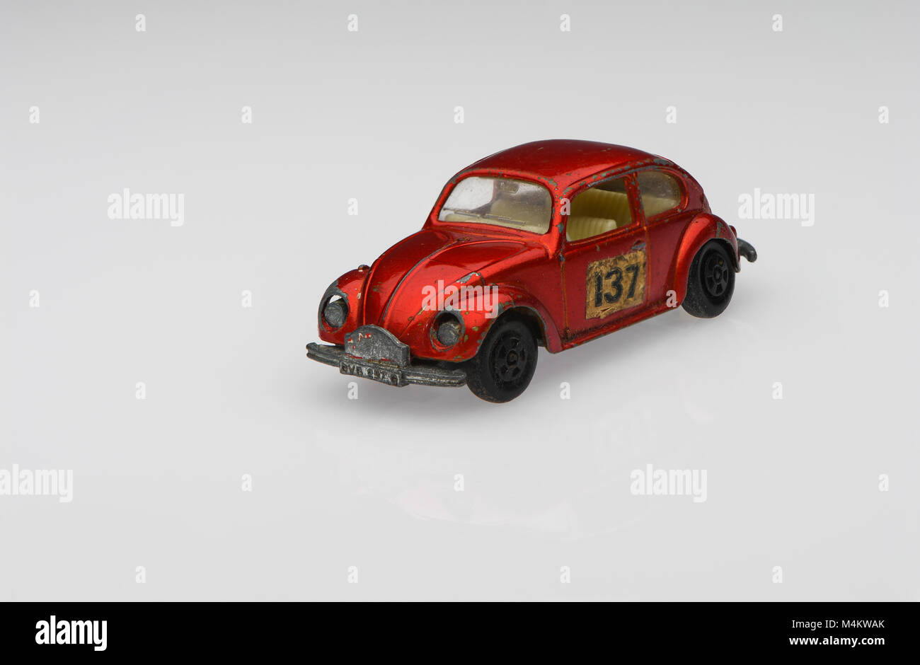 Une berline rouge vintage 1500 Volkswagen voiture de course voiture jouet montrant des signes d'utilisation sur un fond blanc. Banque D'Images