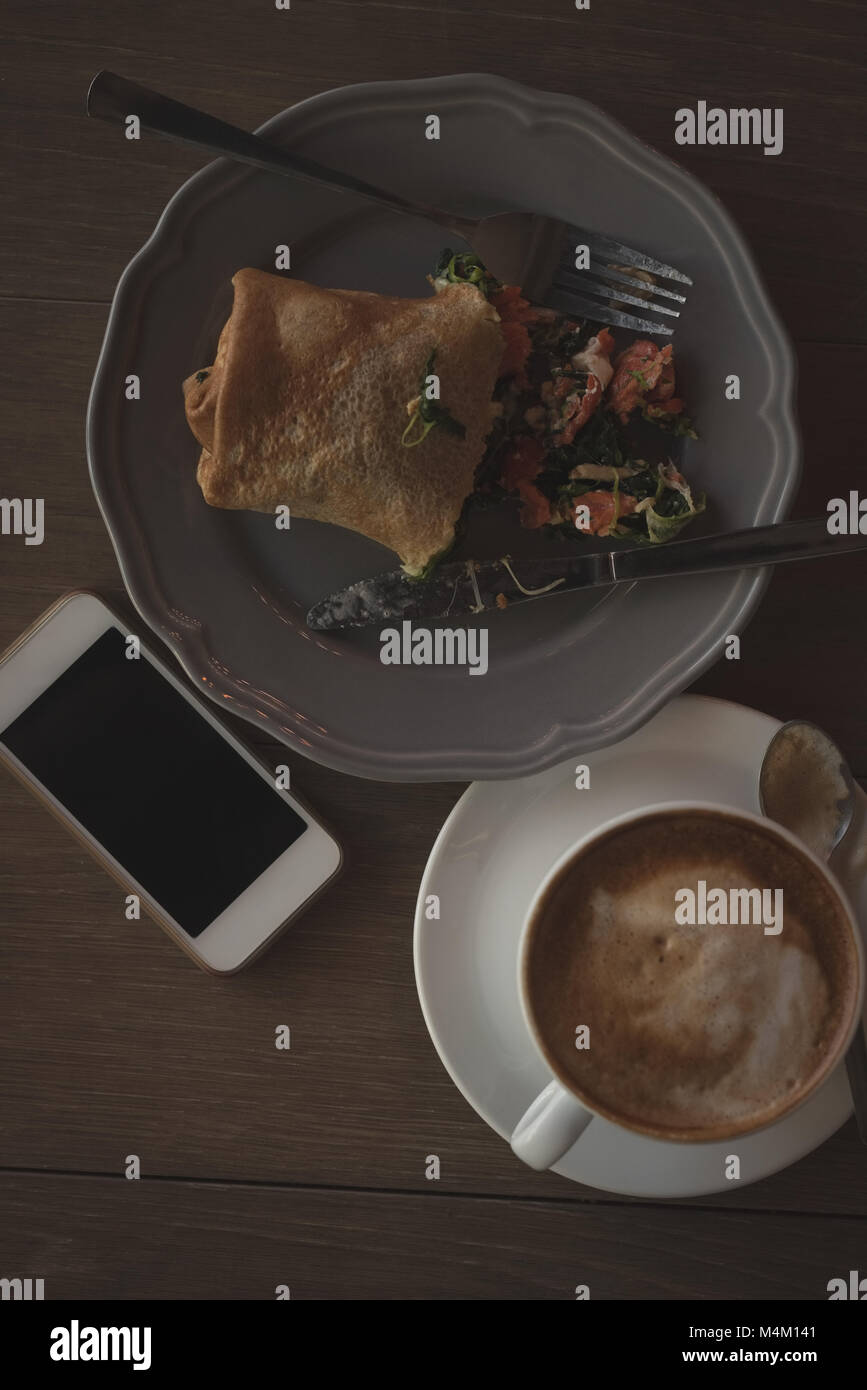 Tasse de cappuccino avec l'alimentation et l'enrubannage table sur téléphone mobile Banque D'Images