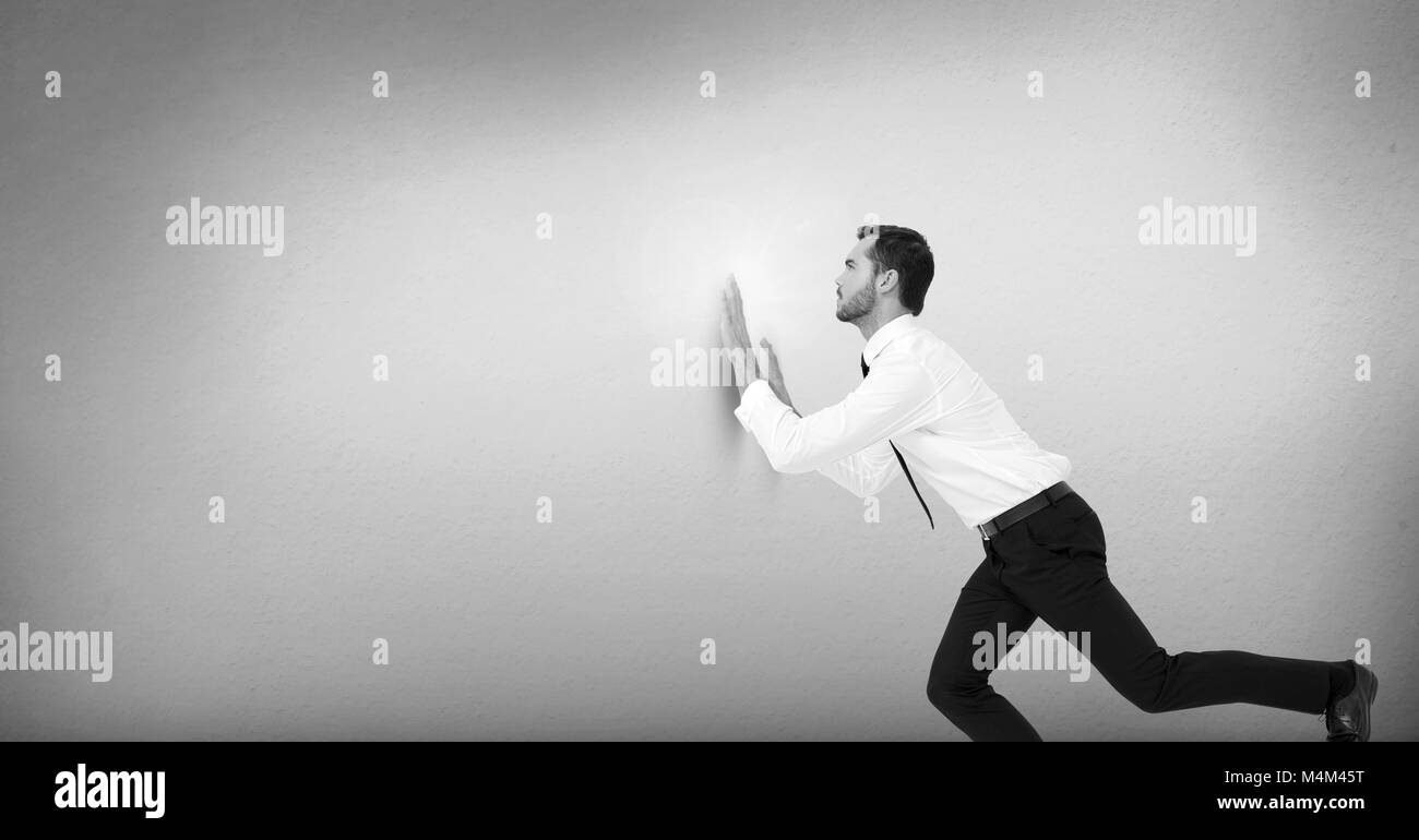 Businessman pushing against wall Banque D'Images