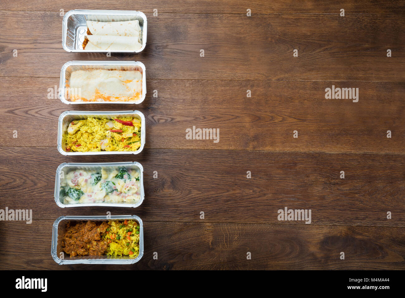 Rangée de plats à emporter dans une feuille contenant sur table en bois Banque D'Images