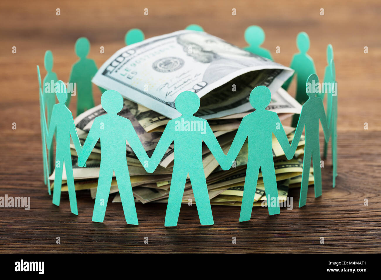 Concept Crowdfunding. Paper Cut Out figures humaines autour de la pile de centaines de Dollar Bills Banque D'Images