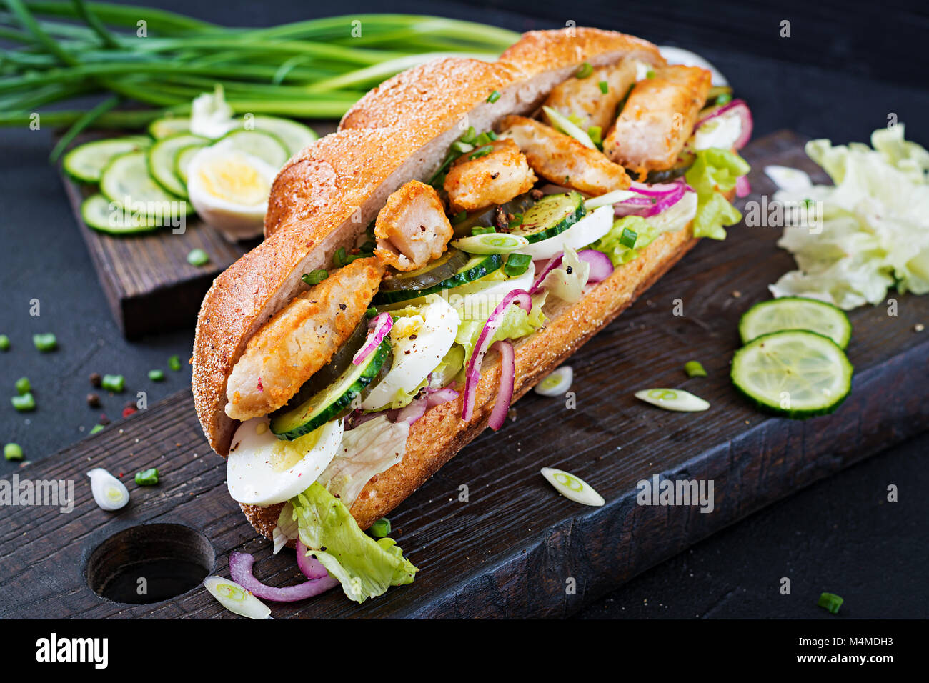 Sandwich baguette avec du poisson, des oeufs, oignons confits et de feuilles de laitue. Banque D'Images