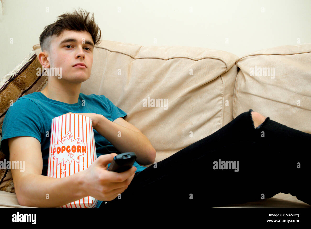 Teenage boy sur un sofa eating popcorn Banque D'Images