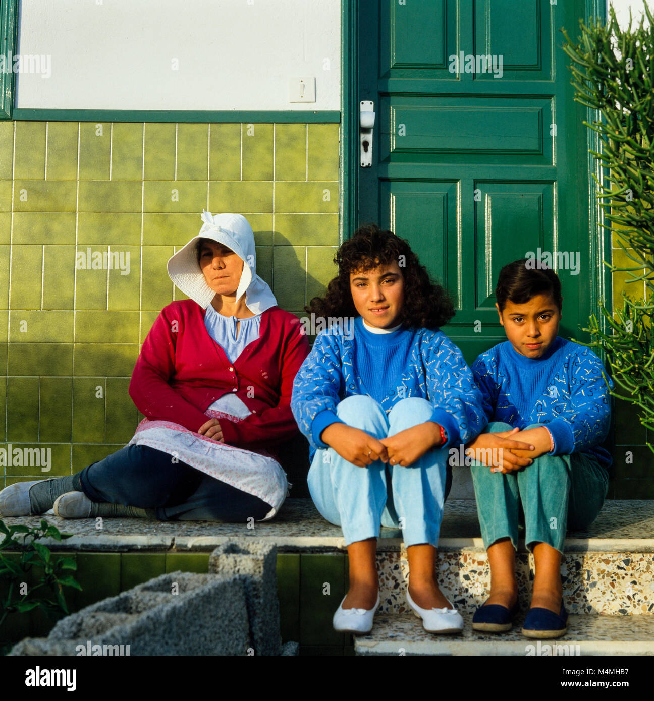 Femme portant un bonnet blanc, et de deux jeunes filles assis au soleil sur les marches d'une maison, Lanzarote, Canaries, Espagne, photographie prise d'archives Janvier 1988 Banque D'Images