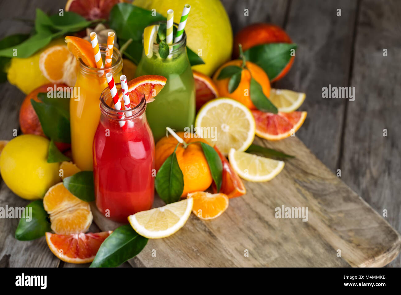Fresh orange, jus d'orange sanguine et de limonade fait maison dans de petites bouteilles sur la vieille table en bois. Copie espace arrière-plan. Banque D'Images