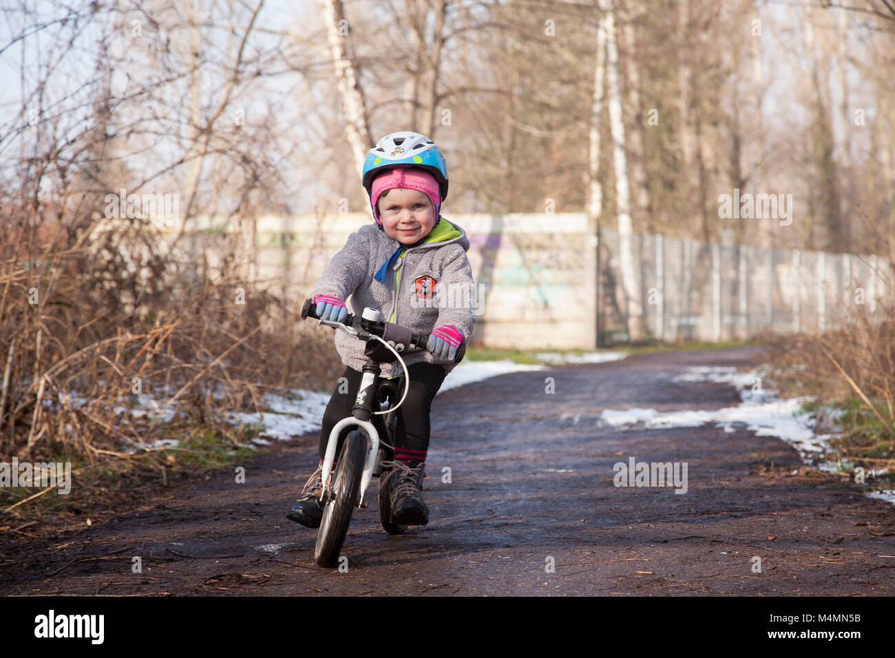 Happy little girl s'amuser dans la nature à côté du mur de graffiti et apprendre à conduire son premier vélo Banque D'Images