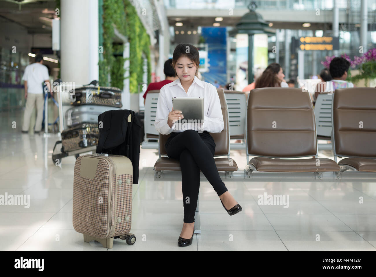 Jeune femme asiatique passager à l'aéroport, en utilisant son ordinateur tablette en attendant son vol dans le terminal à l'aéroport. Banque D'Images