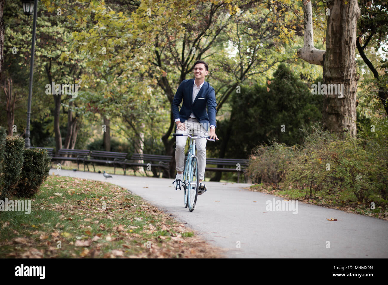 Jeune homme d'une bicyclette à l'extérieur dans le parc. Se rendre au travail en vélo. Banque D'Images