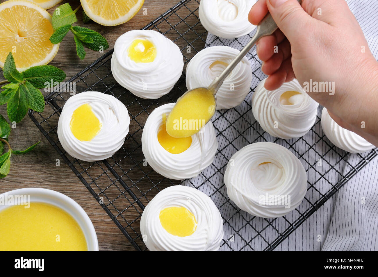 Remplissage d'un kurde de citron, un délicat, mini-dessert croustillant "Pavlova" sur le rack Banque D'Images