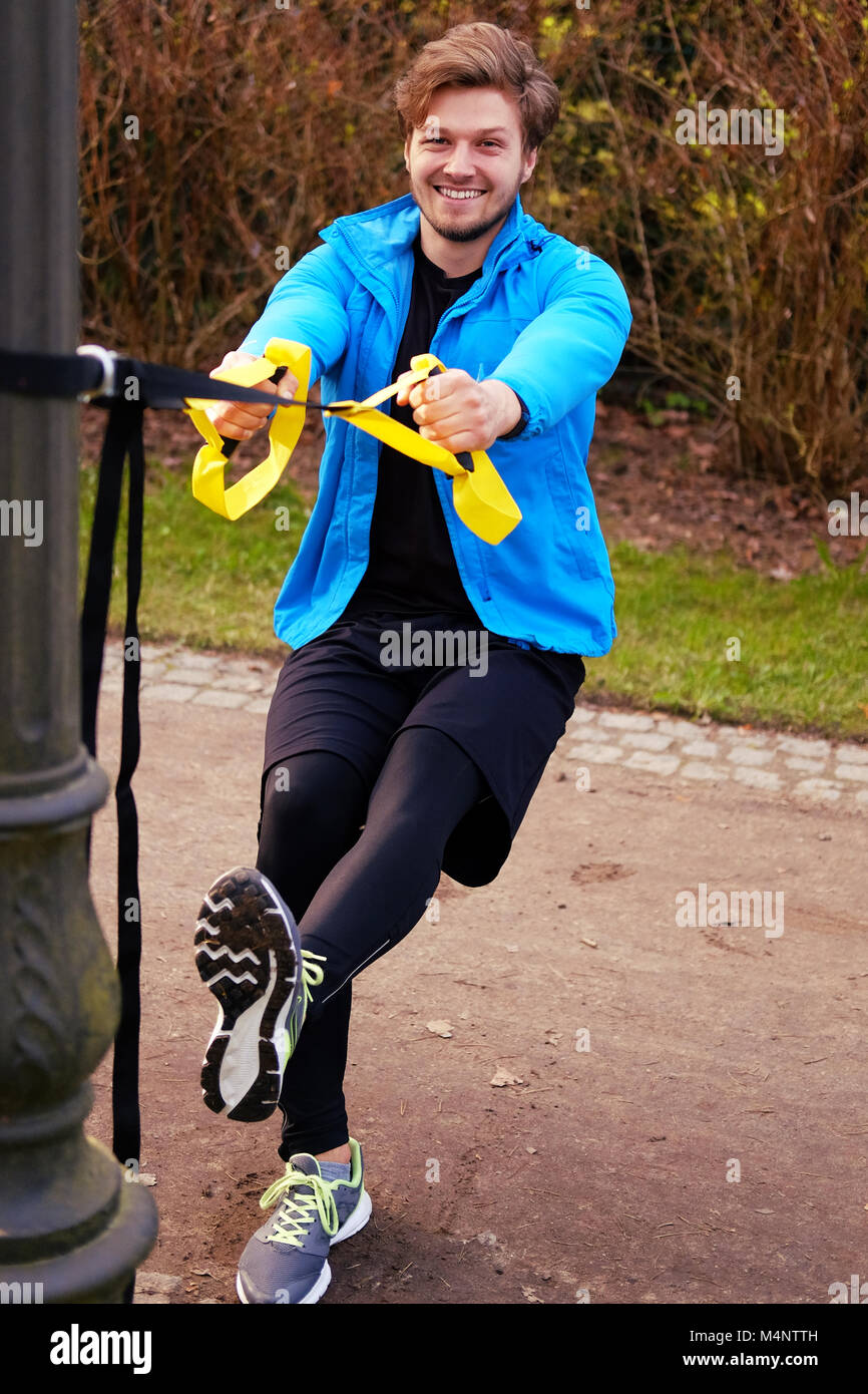 Remise en forme dans un modèle homme veste sport bleu faisant entraînement avec bandes trx fitness dans un parc. Banque D'Images