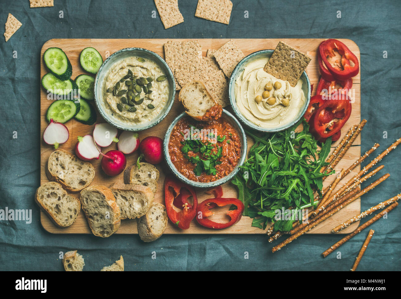 Vegan snack-conseil. Télévision-laïcs de divers dips végétarien, de l'hummus et babaganush muhammara avec des craquelins, du pain, des légumes sur planche de bois plus gr Banque D'Images