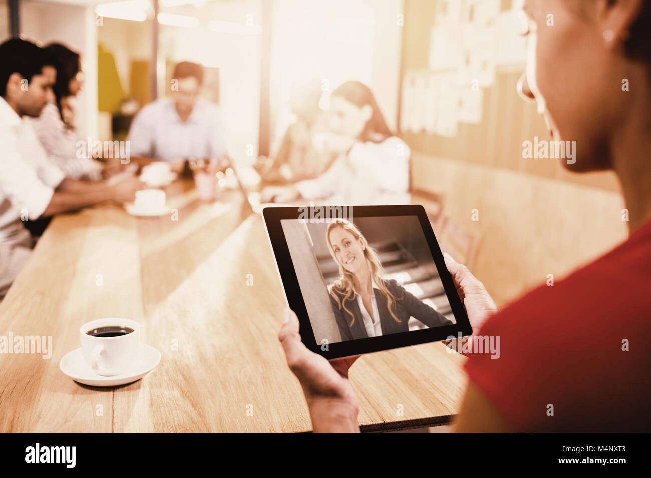 Image composite de woman holding digital tablet avec des collègues en arrière-plan Banque D'Images