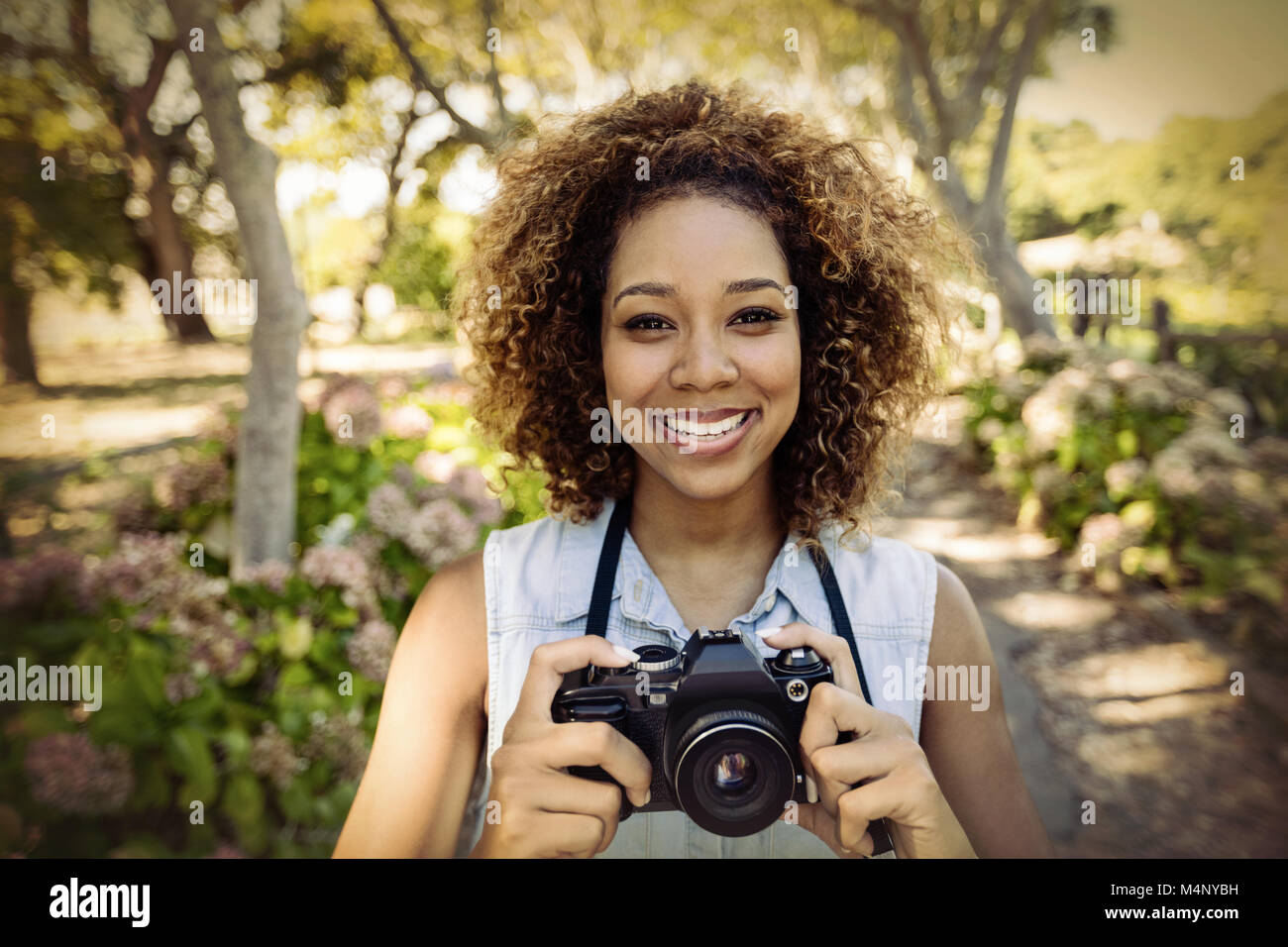 Portrait of smiling woman standing with digital camera Banque D'Images