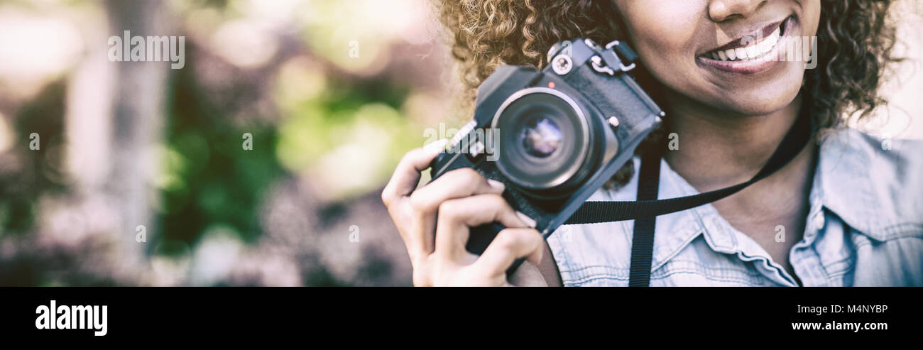 Smiling woman with digital camera at park Banque D'Images