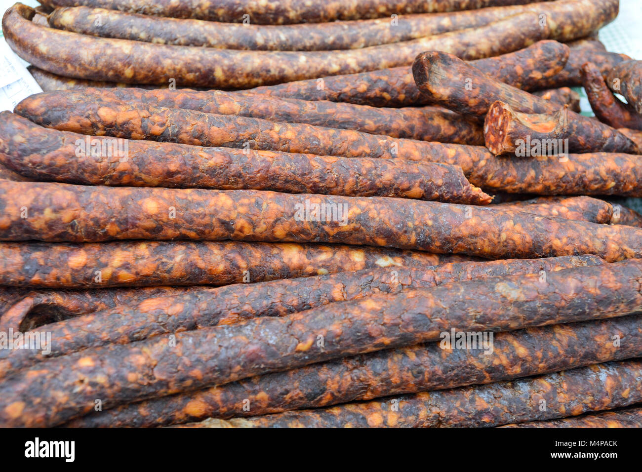 Des saucisses de porc fumé et séché debout sur la table pour la vente. Banque D'Images Des saucisses de porc fumé et séché debout sur la table pour la vente. Banque D'Images