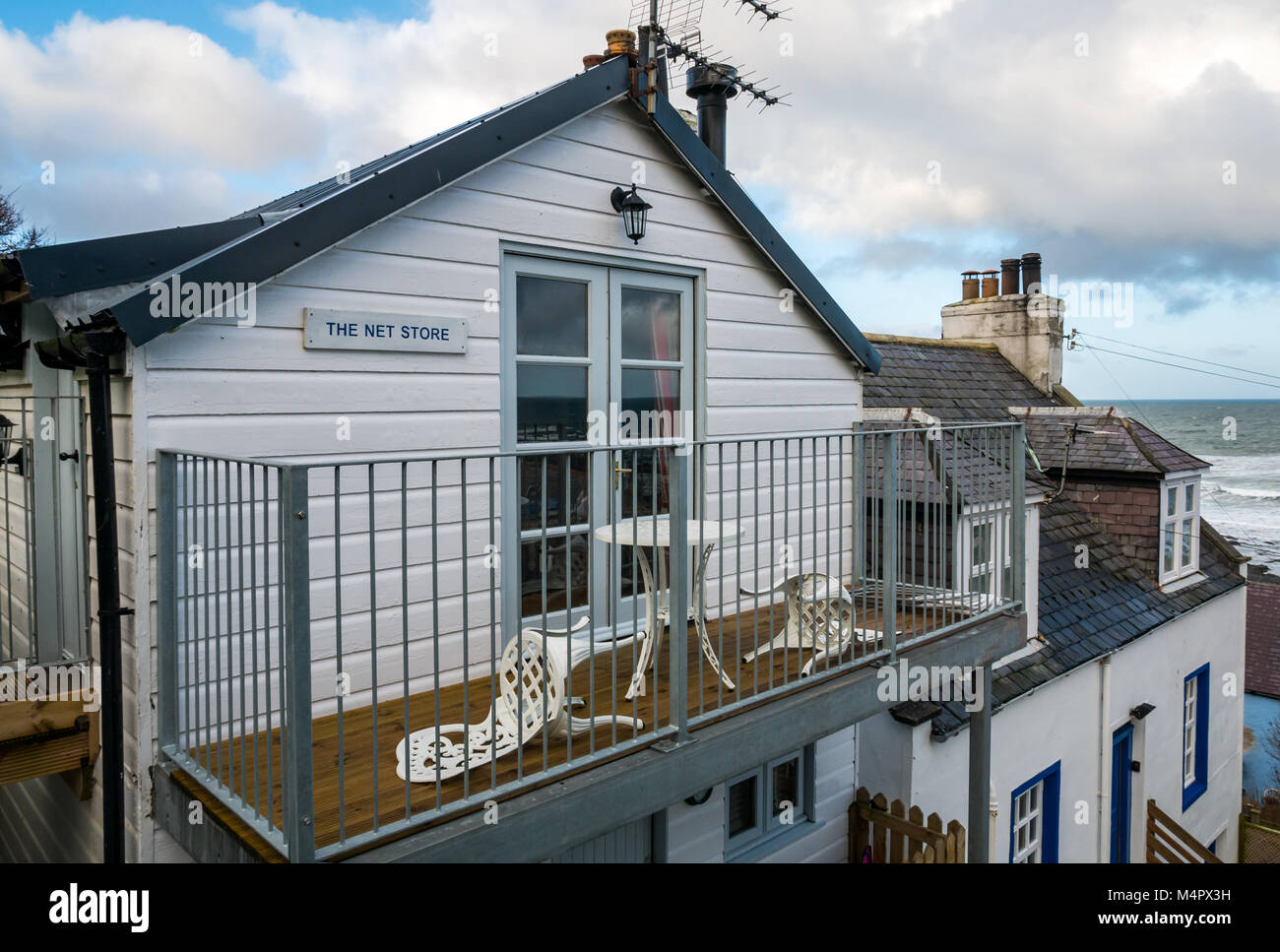 Petit cottage appelé le magasin Net, pittoresque village maritime, Gardenstown, Aberdeenshire, Scotland, UK, avec balcon vue mer Banque D'Images
