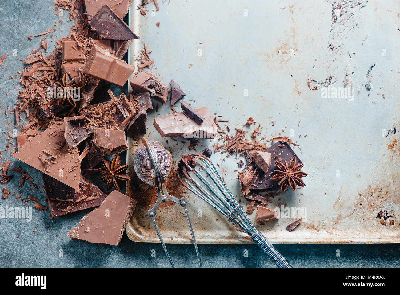 Le chocolat de cuisson à la maison. Dessert ingrédients, poudre de cacao, la cannelle et anis étoile sur une table de cuisine en marbre avec un fouet pour vitrage et un cacao Banque D'Images