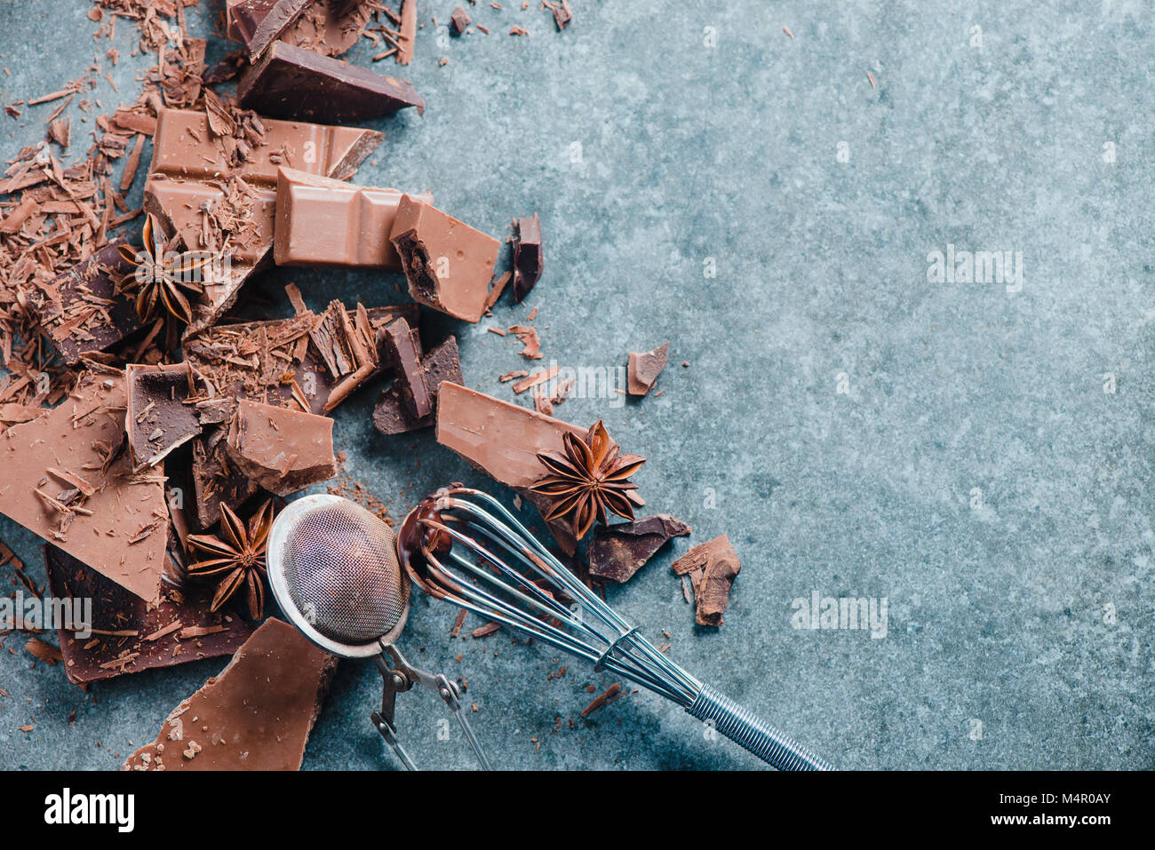 Le chocolat de cuisson à la maison. Dessert ingrédients, poudre de cacao, la cannelle et anis étoile sur une table de cuisine en marbre avec un fouet pour vitrage et un cacao Banque D'Images