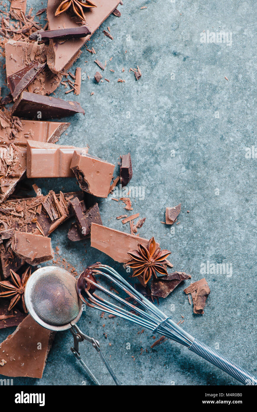 Le chocolat de cuisson à la maison. Dessert ingrédients, poudre de cacao, la cannelle et anis étoile sur une table de cuisine en marbre avec un fouet pour vitrage et un cacao Banque D'Images