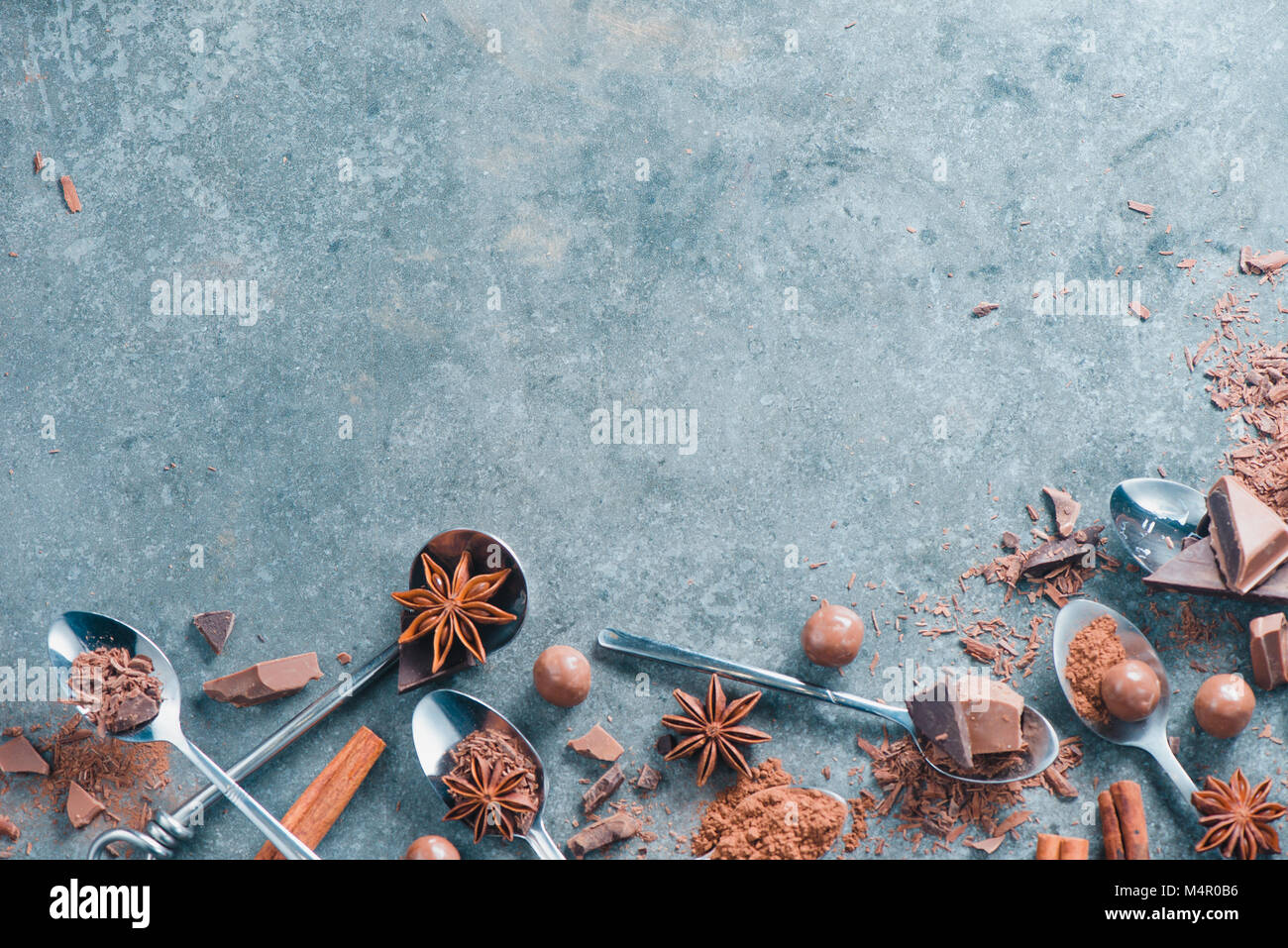 Recette Dessert cuillères frontière avec rempli de pièces en chocolat, d'épices, d'anis étoile, la cannelle et cacao sur un fond de pierre. Ingrédients pour un desse Banque D'Images