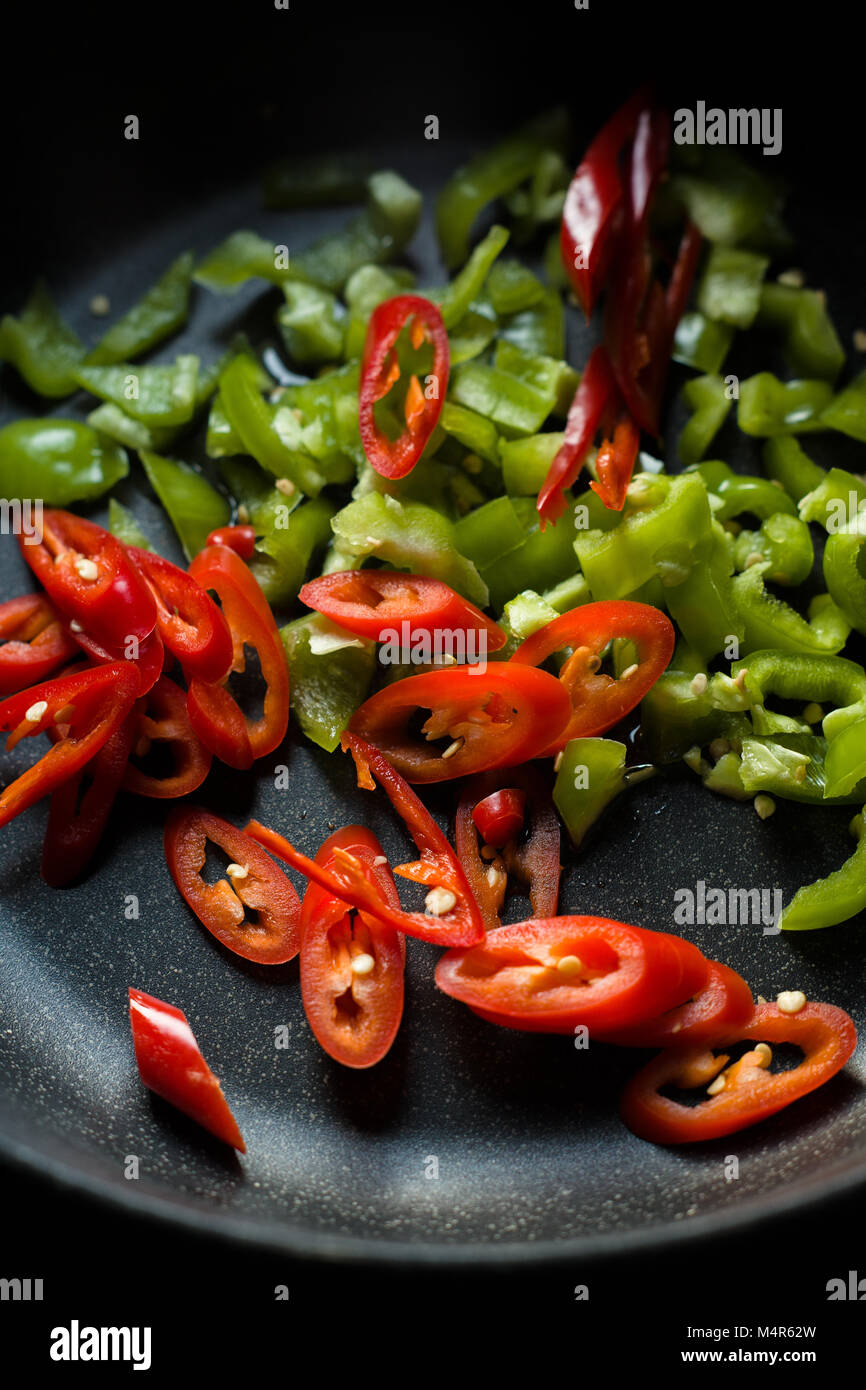 Poivrons verts et rouges pour fajita dans une poêle vertical gros plan ...
