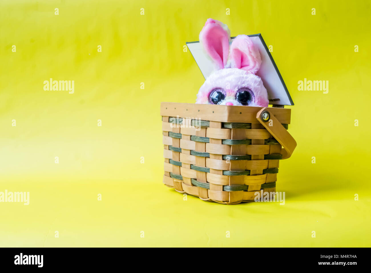 Lapin de Pâques avec panier sur un fond jaune. Banque D'Images