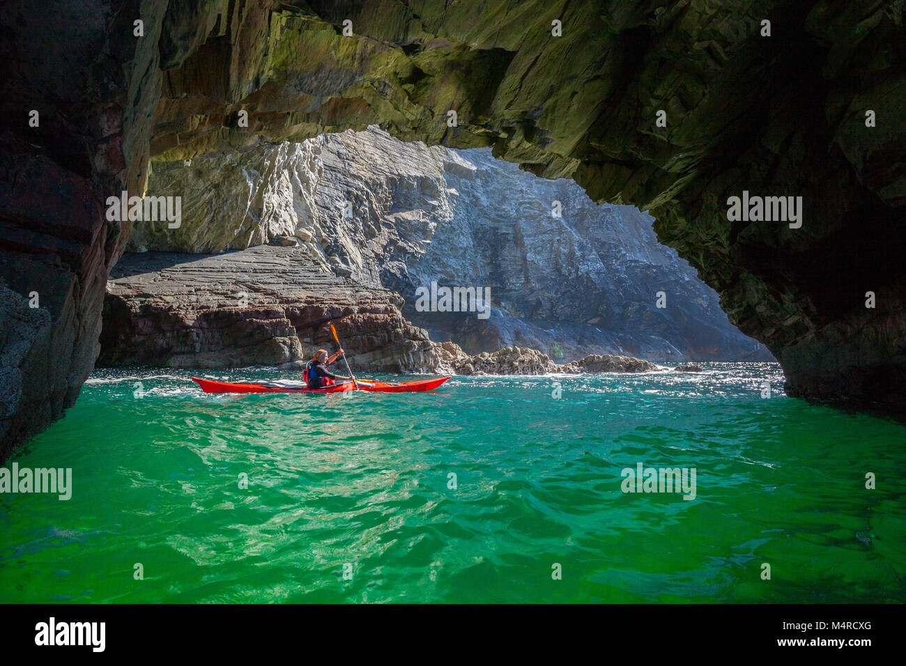 Kayakiste de mer à la découverte d'une grotte près de Glencolmcille, comté de Donegal, Irlande. Banque D'Images