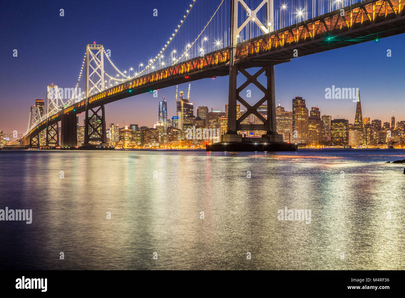 Classic vue panoramique de célèbre Oakland Bay Bridge avec la skyline de San Francisco illuminée en beau crépuscule après le coucher du soleil en été, Califo Banque D'Images