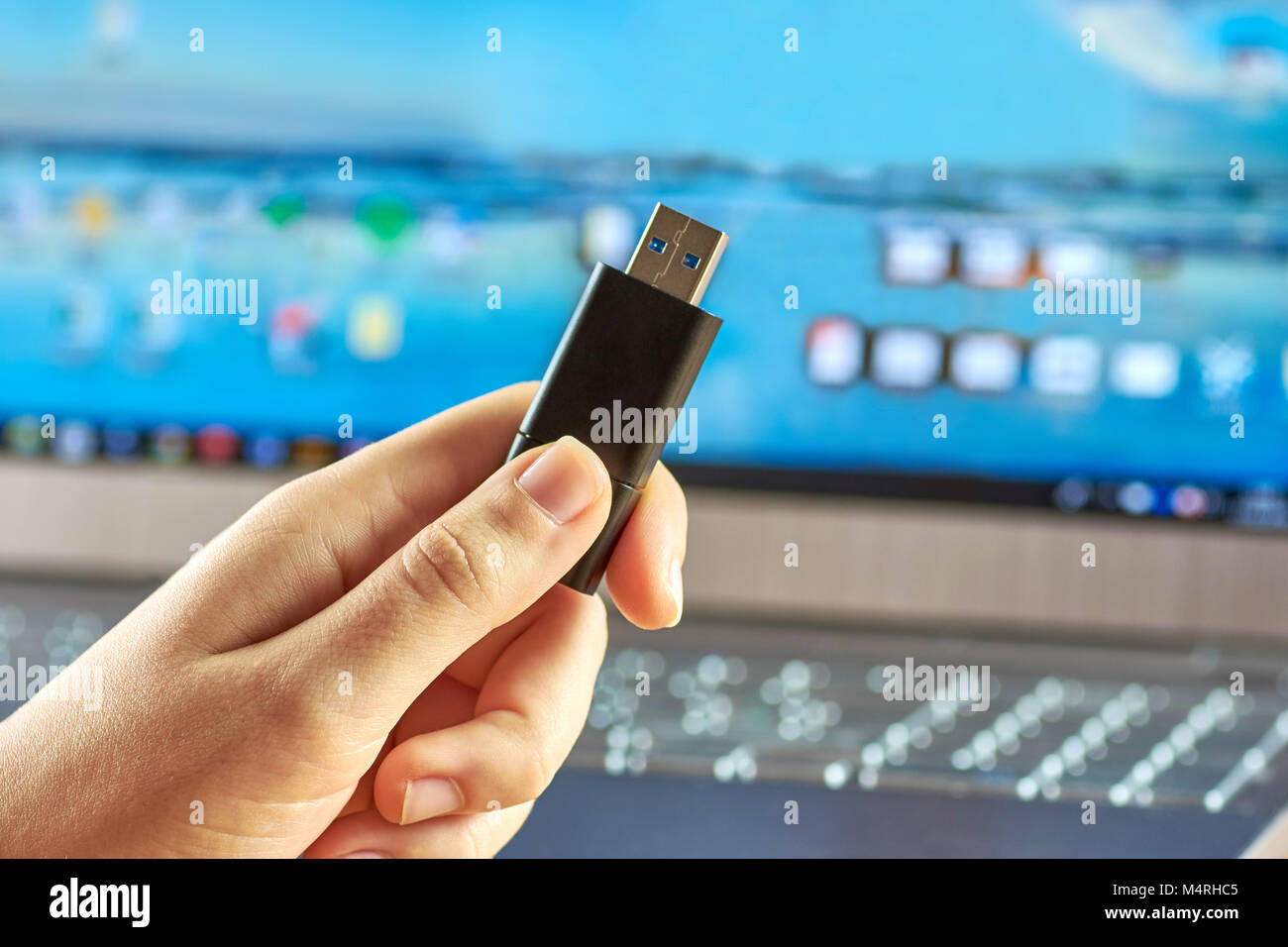 Une main tenant une clé USB avant de l'ordinateur portable est éteint sur argent Banque D'Images