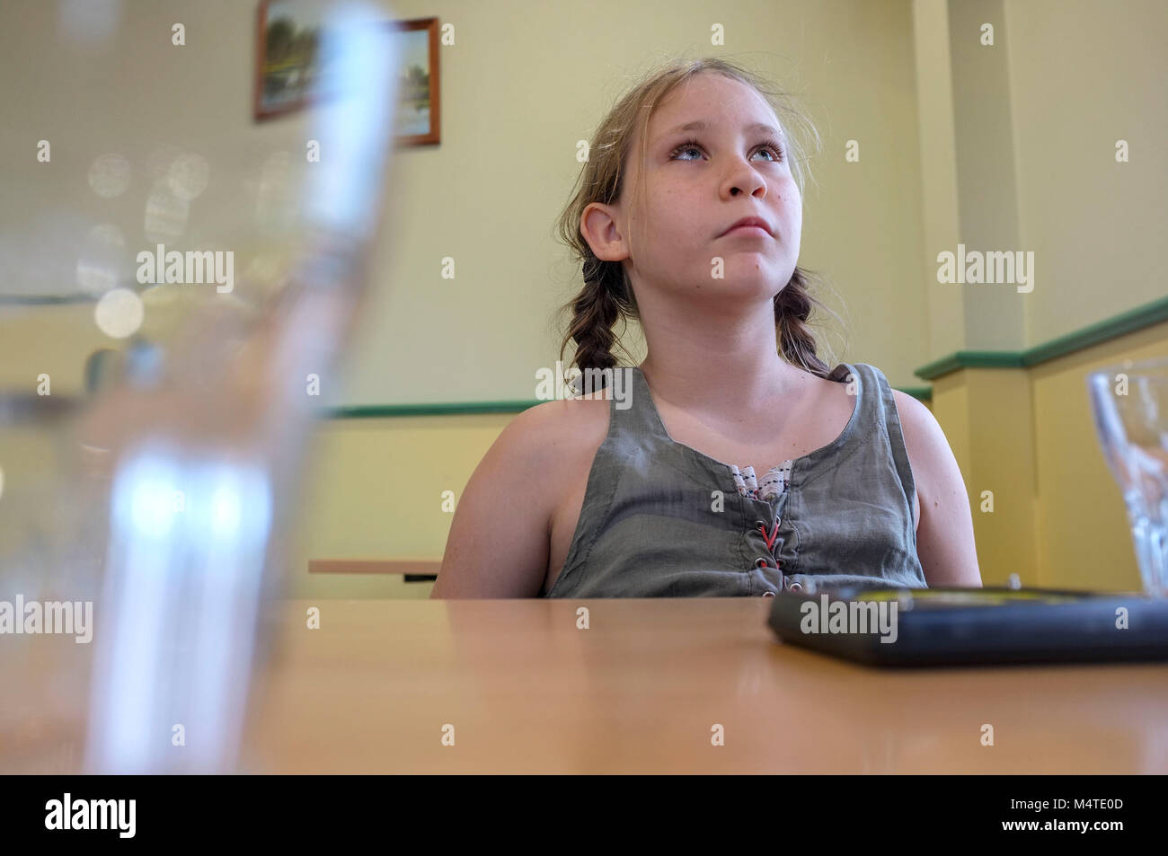 Pre-teen girl et en attente d'un repas dans un pub. Banque D'Images