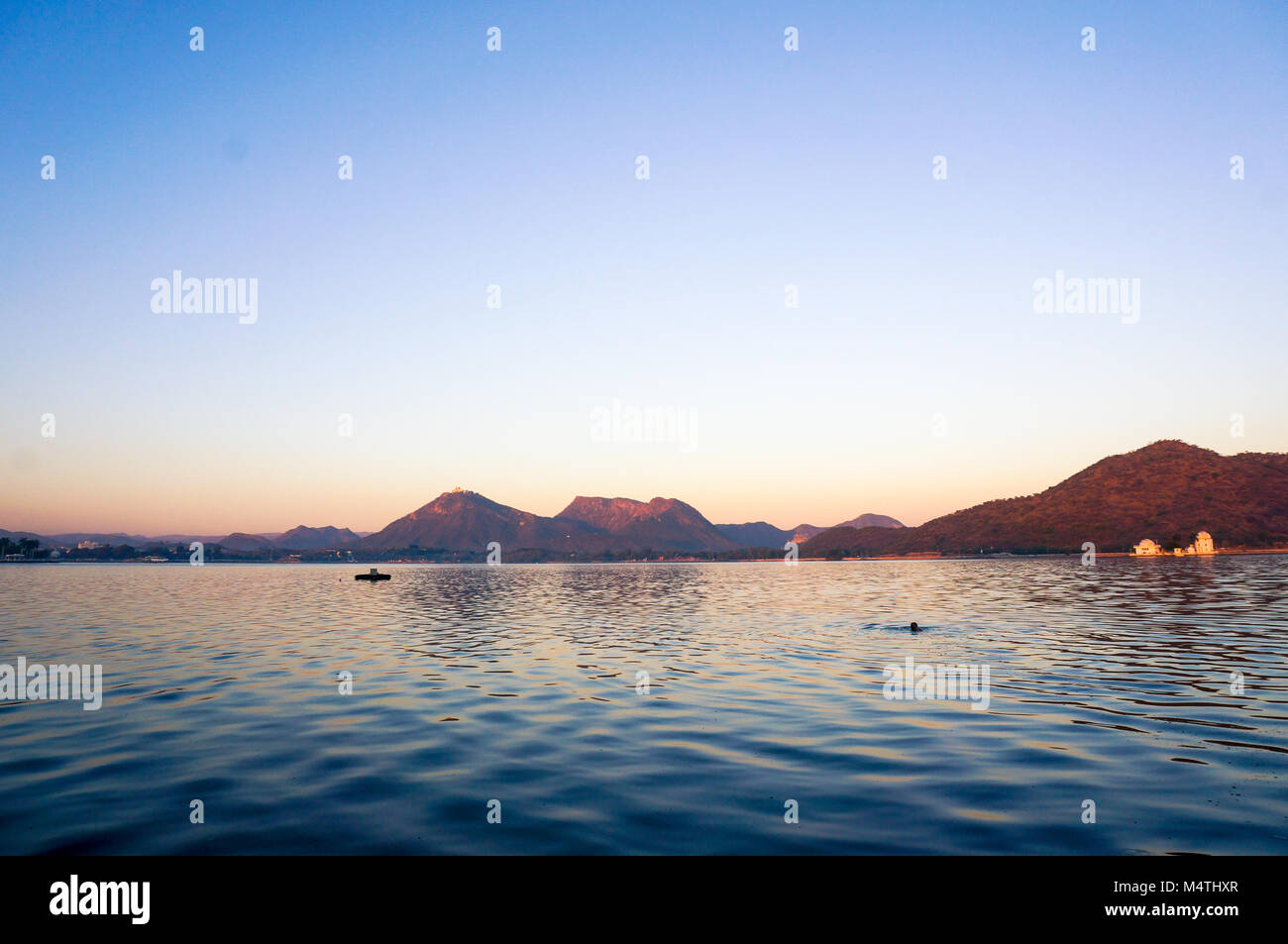 L'aube sereine shot de fateh sagar lake udiapur l'Inde. La belle eau bleu avec des vagues et de la lumière d'or dans les collines d'Aravali frappant la distance en font l'un des meilleurs endroits à Udaipur Banque D'Images