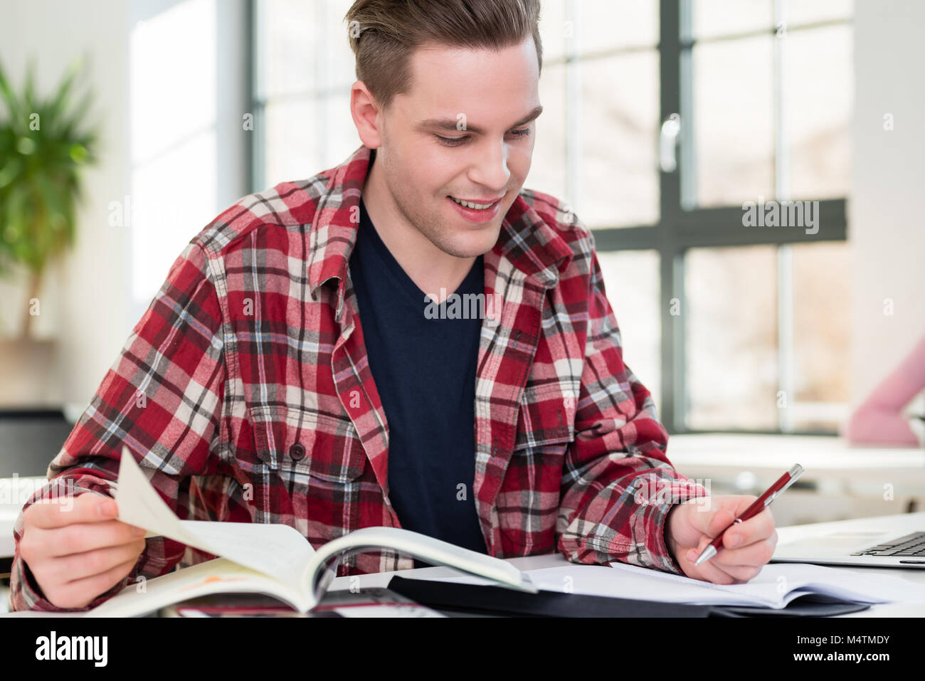 Portrait of a young student smiling tandis que la recherche d'informations Banque D'Images