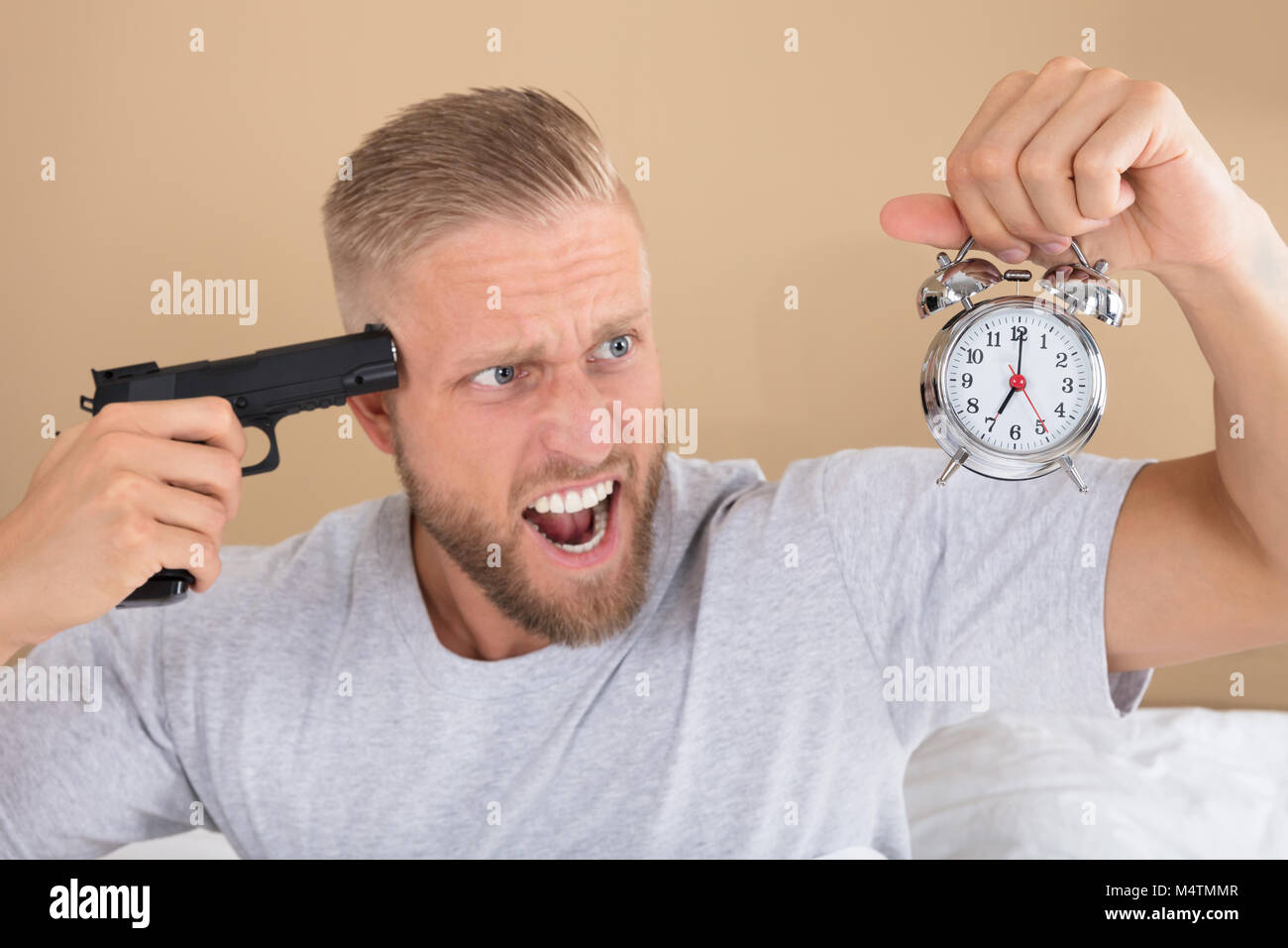 Close-up of a Angry Young Man Holding Gun et Réveil Banque D'Images