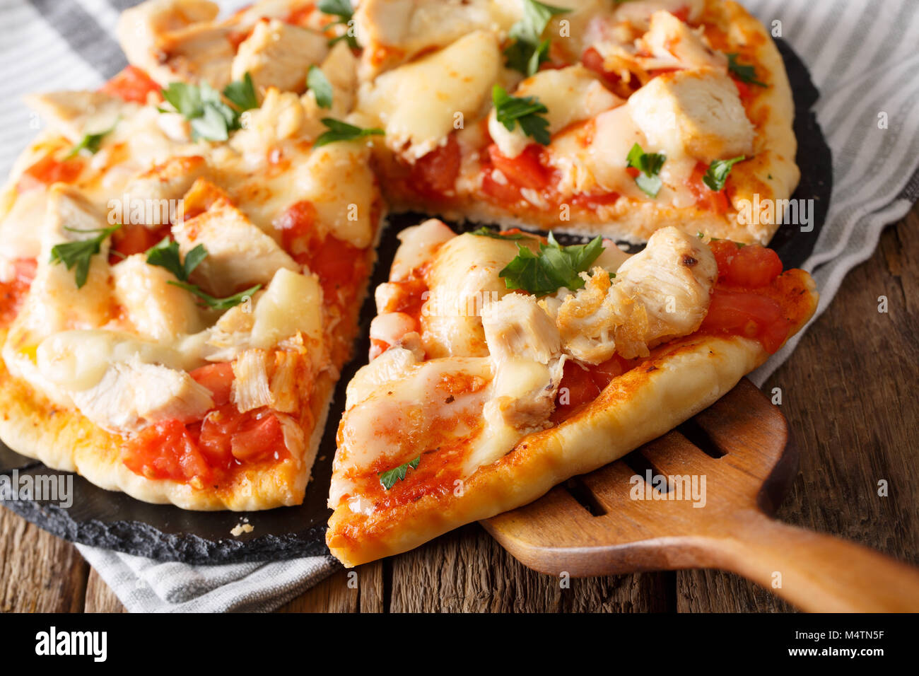 Petites tranches de pizza au poulet buffalo, tomates et fromage macro sur la table horizontale. Banque D'Images