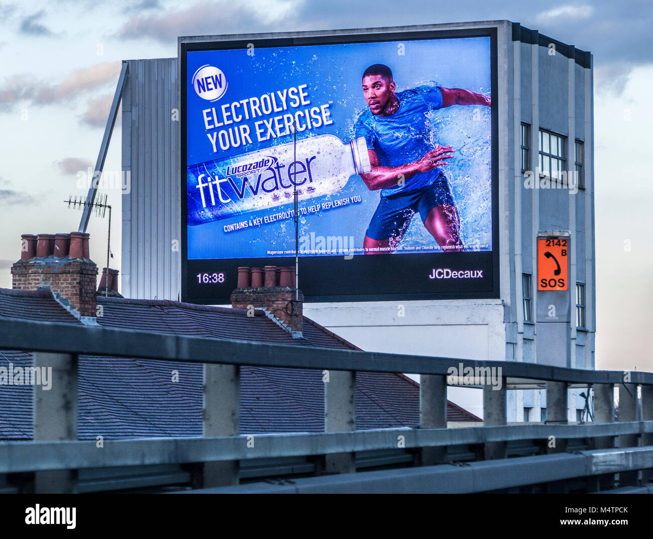 Lucozade affichage numérique sportsman annonce sur le côté d'un bâtiment en béton 1954 historique, à côté de l'autoroute M4, Brentford, Londres, Angleterre, Royaume-Uni. Banque D'Images
