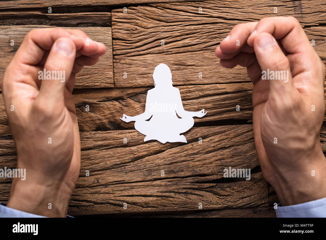 Les doigts de l'homme dans Mudra geste avec Lotus Poser composé de White Paper Cut-out Banque D'Images