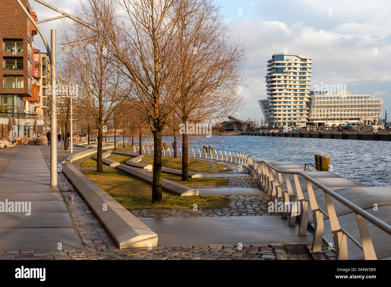 Vue depuis le Grasbrookhaven Dalmannkai étapes au Marco Polo et terrasses à la lumière du jour après une pluie avec arbres chauve en février. Banque D'Images