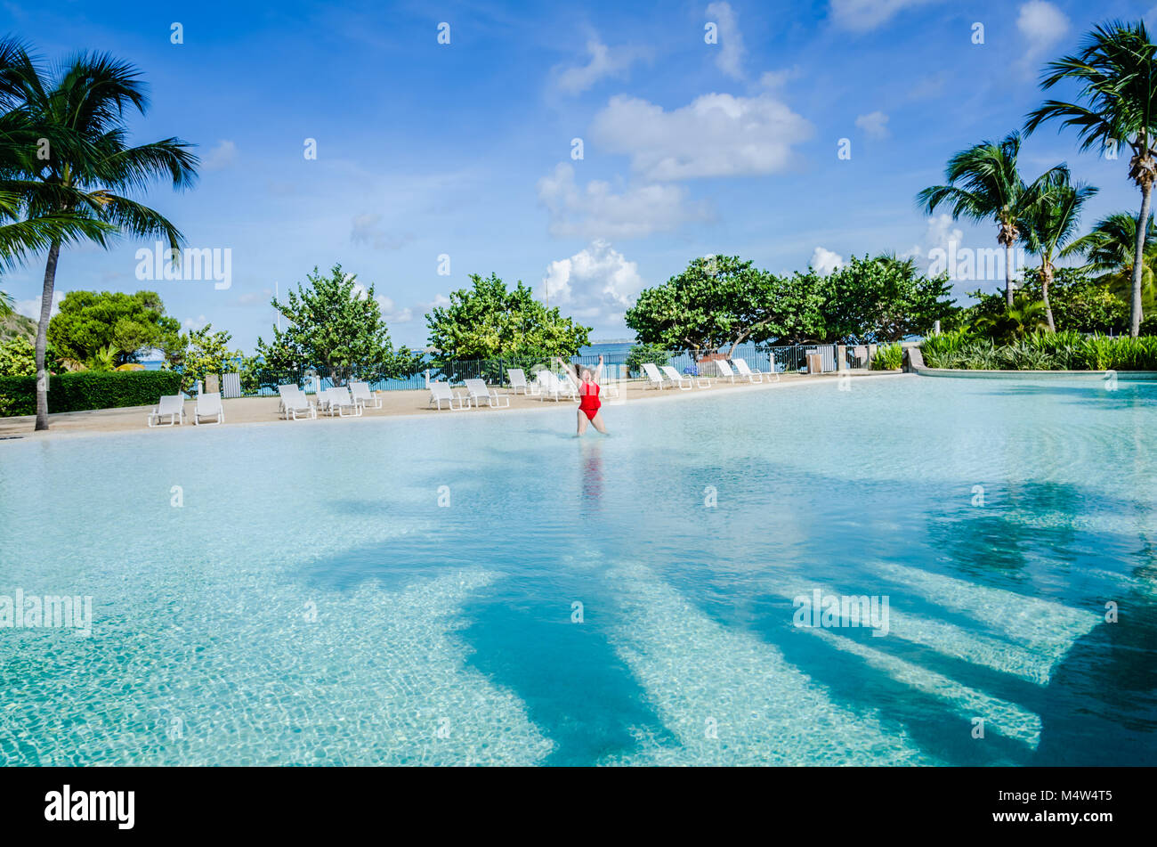 Femme en maillot rouge saute avec l'excitation dans l'une des plus grandes piscines dans les Caraïbes. Banque D'Images
